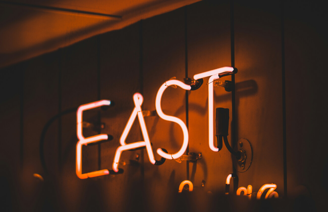 Neon sign that reads East and is lit up in red neon light.